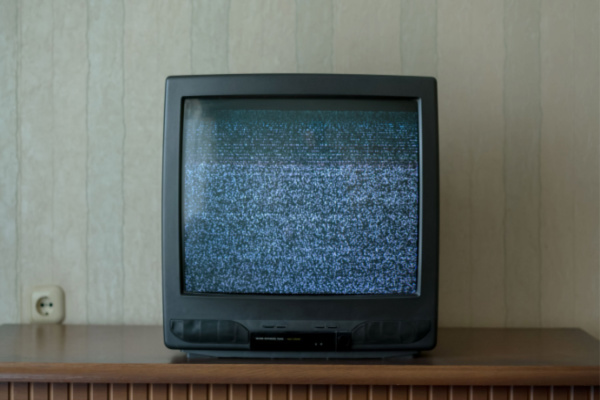 black old TV with static on screen standing on wooden table in room of home