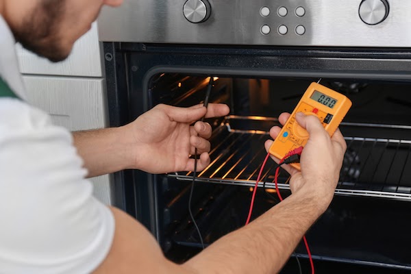 electrician testing electrical amps of electrical oven 