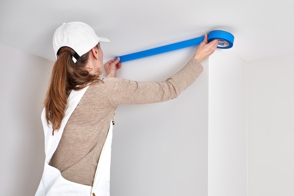 female interior painter taping the ceiling