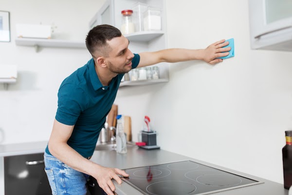 man cleaning kitchen walls during spring cleaning