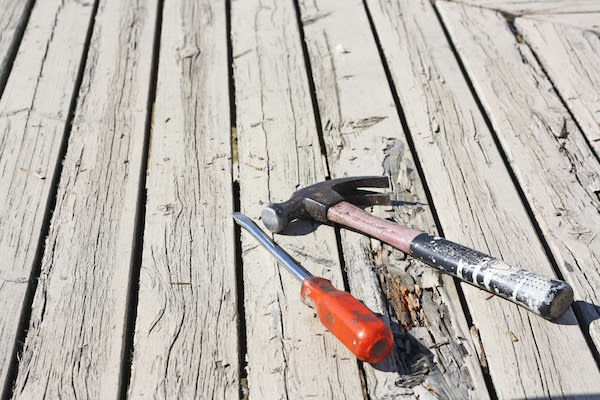 hammer and screwdriver on rotting deck boards