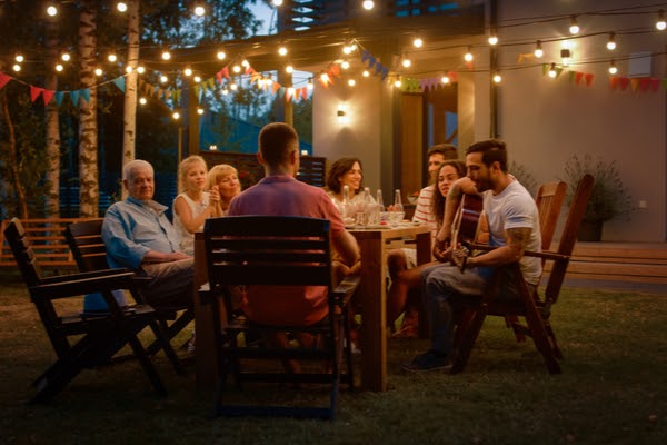 family enjoying backyard around table with lighting