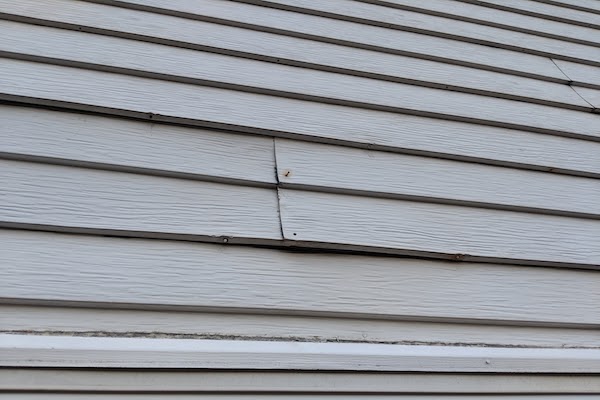 siding showing exposed rusty nails and repairs needed