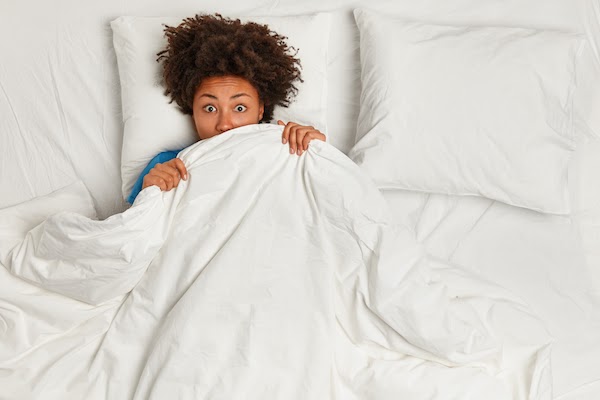 woman scared in bed about bed bugs