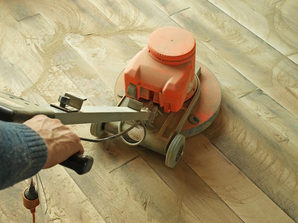 floor being sanded by worker