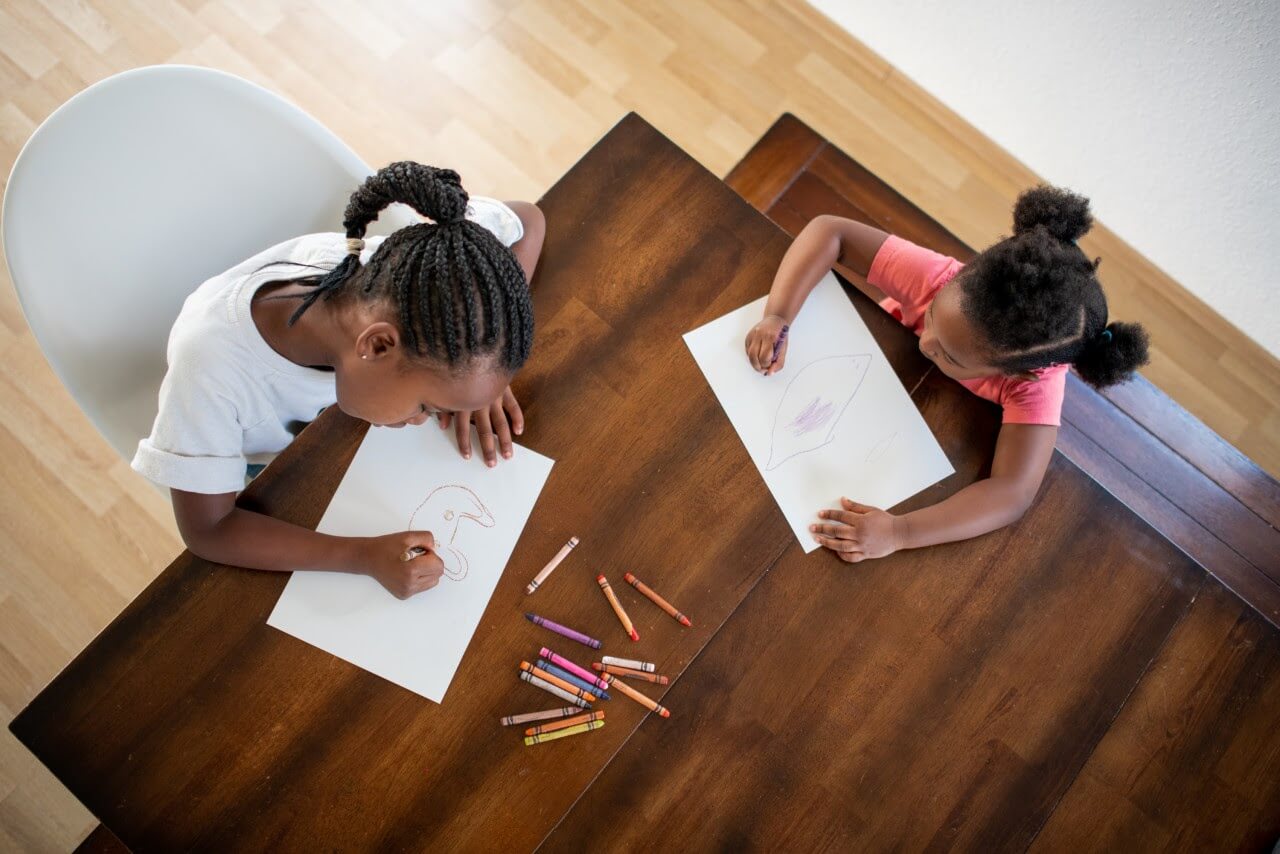 two children sitting at table colouring