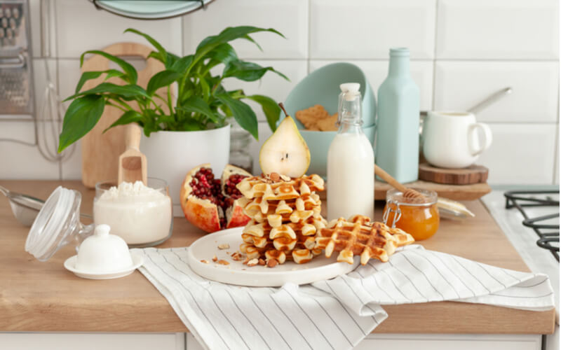 Cooked homemade waffles in the kitchen and the ingredients from which they are made