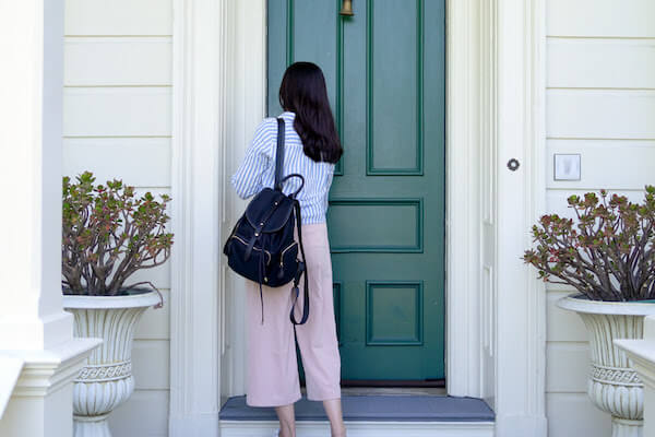 женщина запирает зеленую входную дверь дома