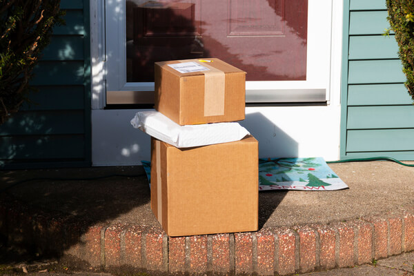 Three packages are delivered to the front stoop of a residential house.