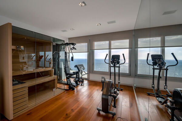 Sauna and fitness room with sea view. Traditional finnish sauna made from woodand glass door design in the sauna. Concept of: relax, vacation, wellness center.