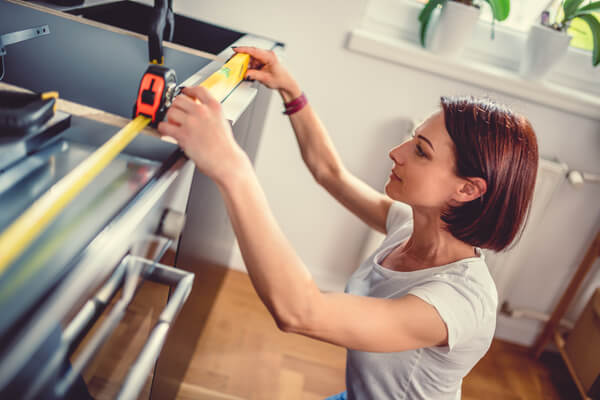 Woman working on a new kitchen installation and using leveling tool