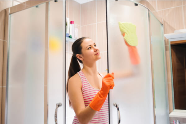 portrait of young woman cleaning shower door