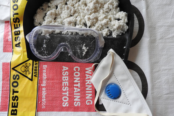 Closeup asbestos and fibers, mask, filter and goggles. Asbestos bag in the background. Barrier tape, warning forbidden acces hazard. Asbestos removal. Asbestosis, lungcancer or mesothelioma, serie.