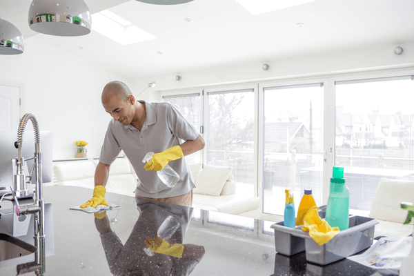 Shot of a young mixed race man cleaning a kitchen top. The kitchen is an open planned and spacious.
