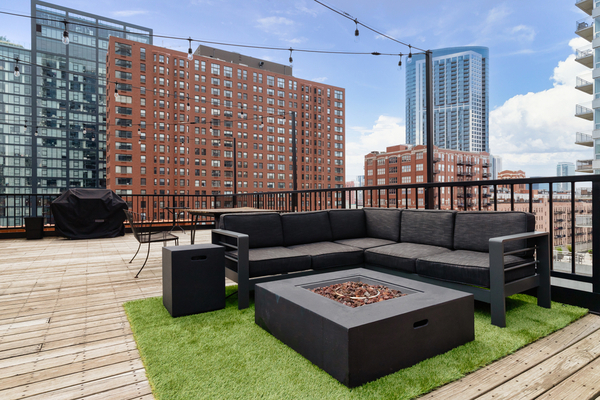 CHICAGO, IL, USA - AUGUST 12, 2019: A rooftop patio in Chicago with stairs leading up to a seating area and a string lights overhead. Buildings are in the back background with a blue sky and clouds.