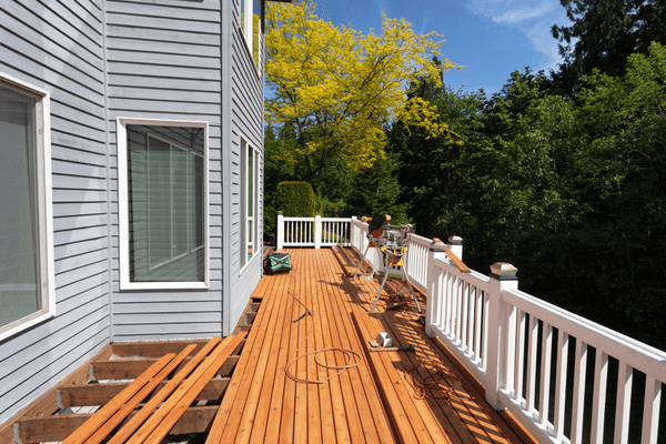 Outdoor wooden deck being remodeled with new red cedar wood floor boards being installed