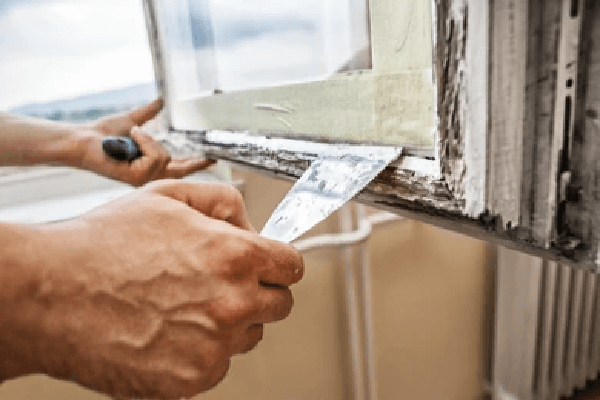man working on removing paint from old window prepwork for installation of new window