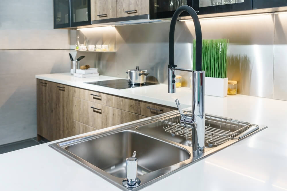 Stainless kitchen sink and Tap water in the kitchen. The interior of the kitchen room of the apartment. Built-In Appliances. Kitchen Appliance. Domestic Appliances